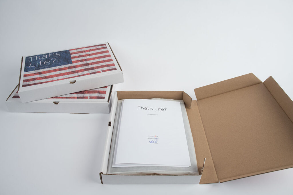 Ansicht der 10er-Edition der künstlerischen Arbeit „That’s Life?“. Der bedruckte Karton besitzt die Außenmaße von 34 cm x 24 cm. Im Karton befinden sich die 22 Motive der Serie. Jeder Abzug besitzt die Größe von 24 cm x 32 cm. Hinzu kommt noch ein Künstler Kommentar zur Arbeit, gedruckt und signiert.