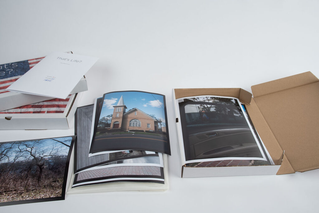 Ansicht der 10er-Edition der künstlerischen Arbeit „That’s Life?“. Der bedruckte Karton besitzt die Außenmaße von 34 cm x 24 cm. Im Karton befinden sich die 22 Motive der Serie. Jeder Abzug besitzt die Größe von 24 cm x 32 cm. Hinzu kommt noch ein Künstler Kommentar zur Arbeit, gedruckt und signiert.